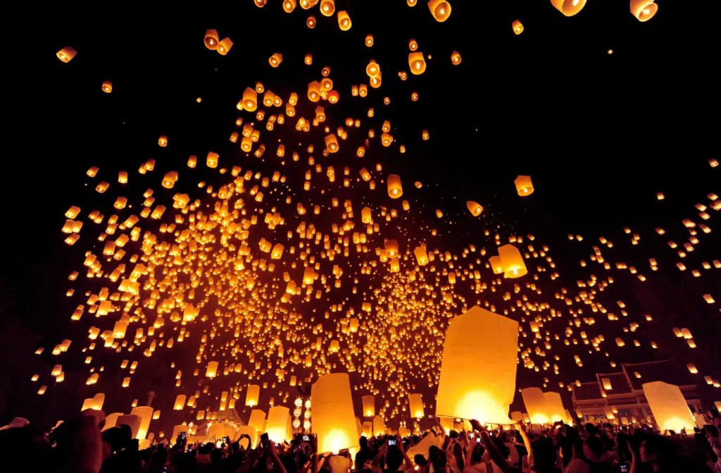 Sky lanterns being released during a festival in Thailand, creating a spectacular display of light against the night sky.